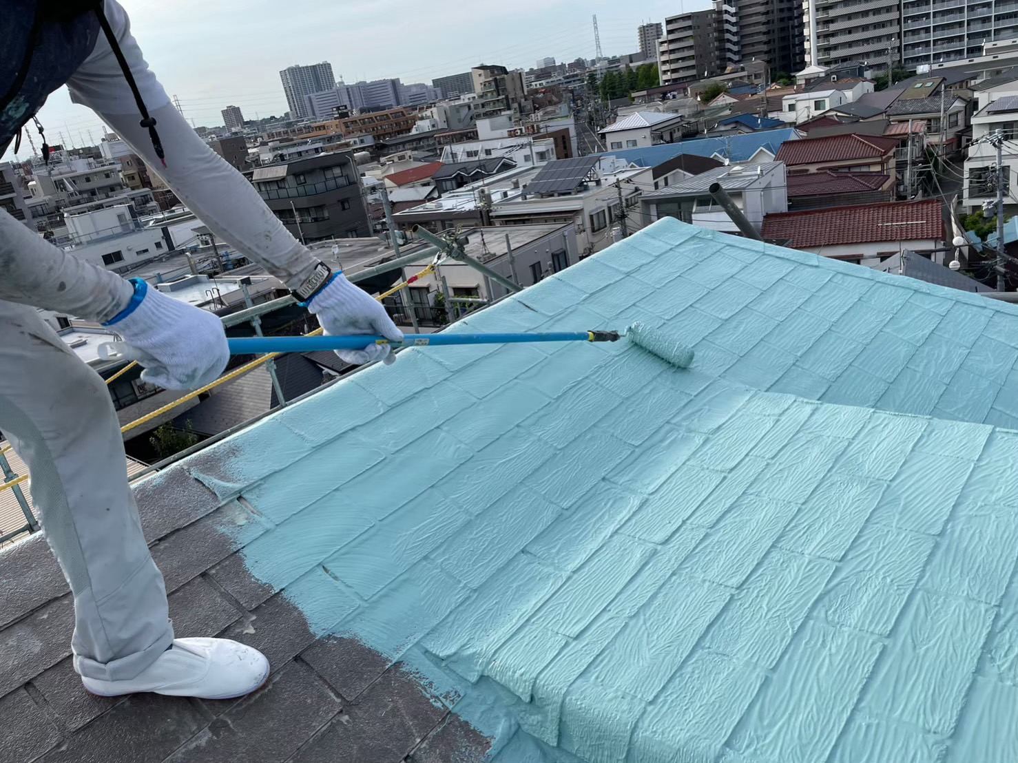 屋根に下塗り材をローラーで塗っている様子
